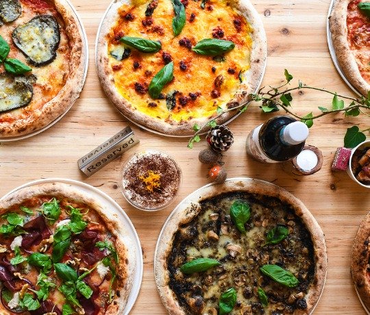 Festive Pizza Feast Looking down directly onto a table with Christmas decorations and lots of pizza options.